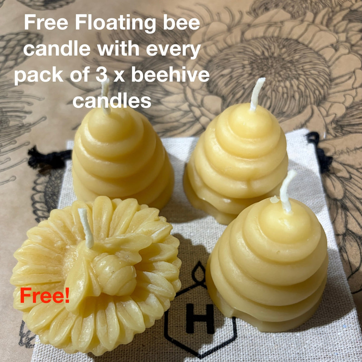 Three beehive-shaped candles with one free bee floating candle on a textured surface with floral patterns.