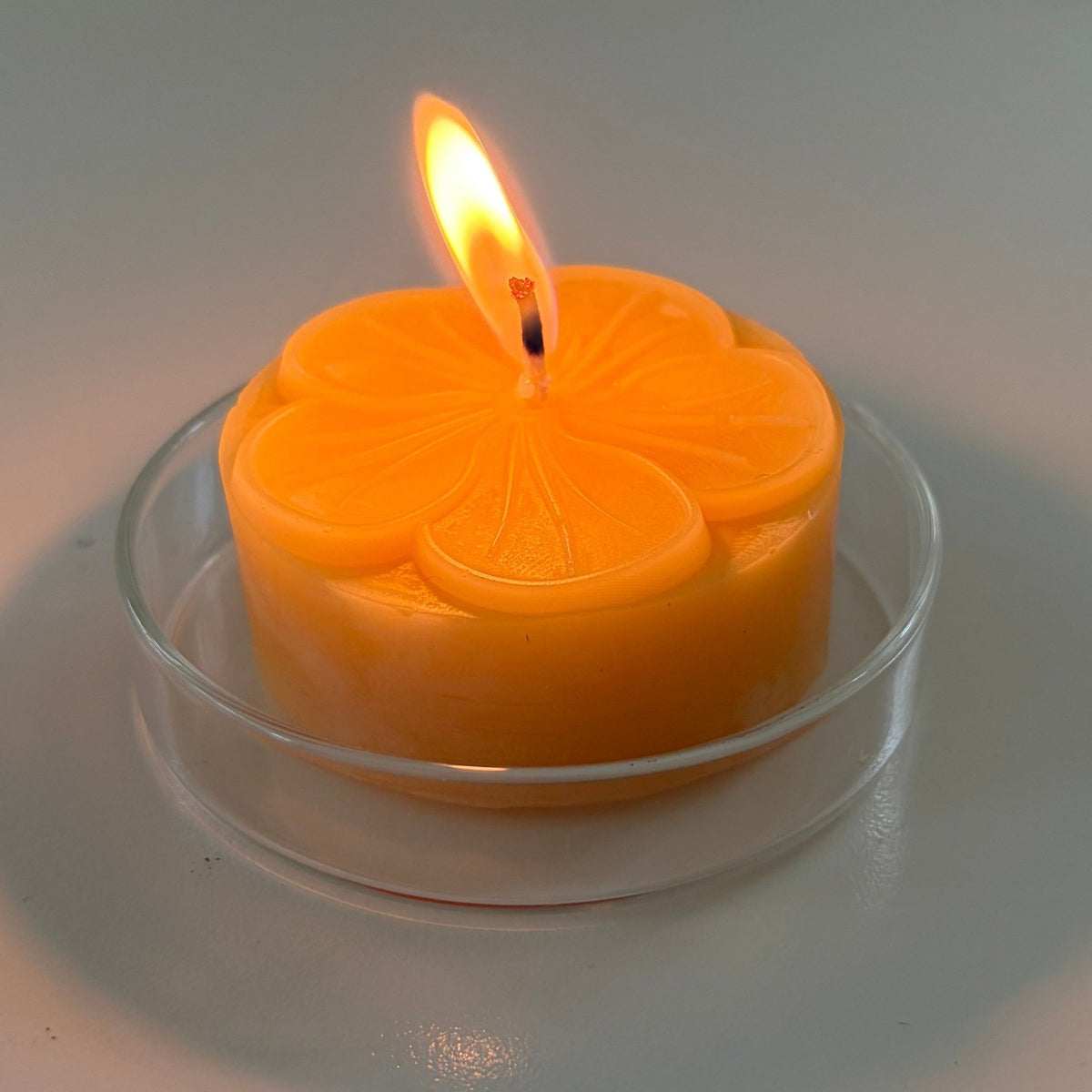 Lit beeswax  candle with a decorative design on a white background