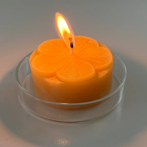 Lit beeswax  candle with a decorative design on a white background