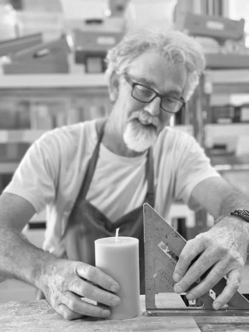 Candle maker straightening a beeswax candle