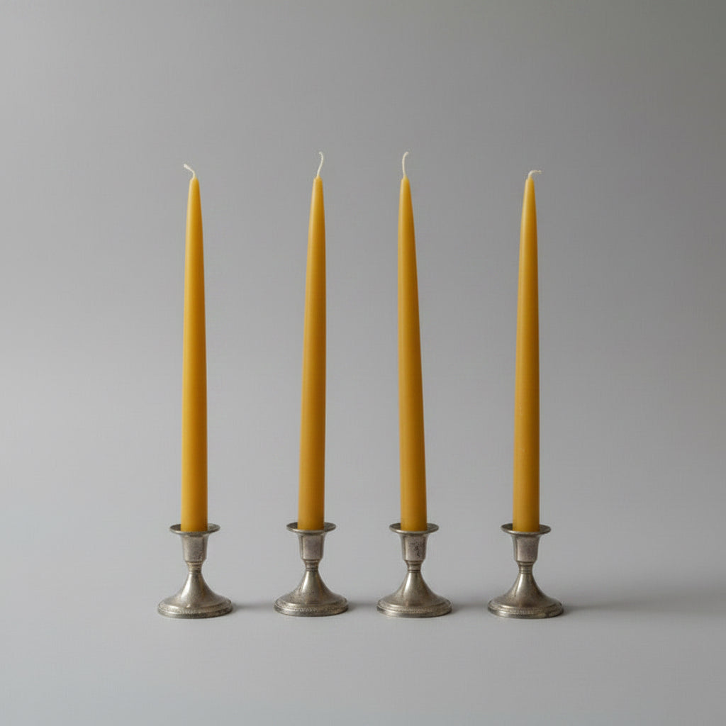 Four yellow candles in silver candle holders on a white background